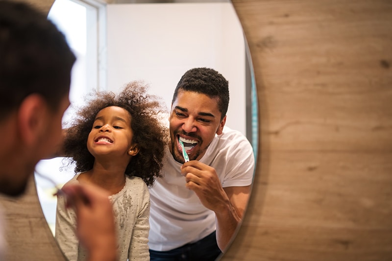 happy kid brushing infront of mirror